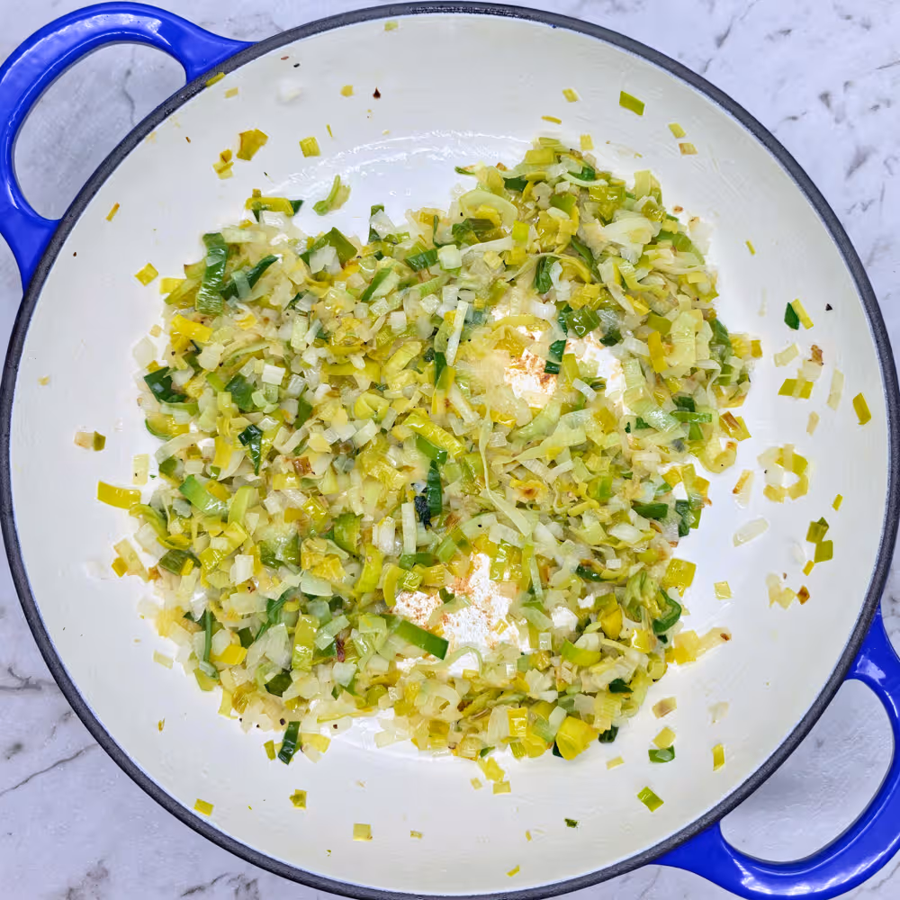  Sliced leeks and finely chopped onion in a frying pan. Lightly caramelised and soft fried leeks and onion. 
