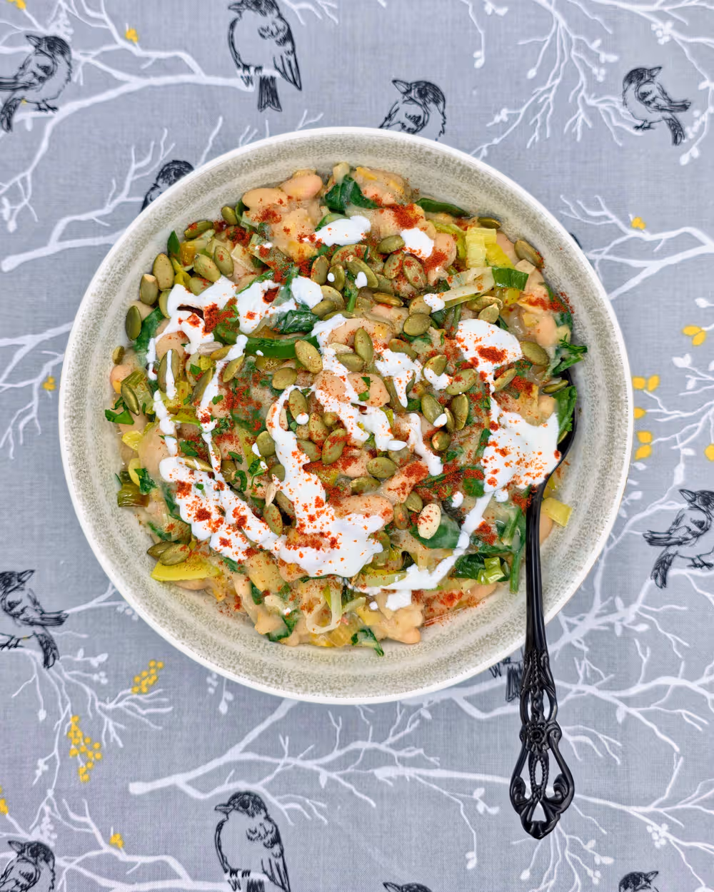  Leeky Beans plated in a bowl and topped with a sprinkle of toasted pumpkin seeds, a drizzle of Greek yoghurt and a sprinkle of smoked paprika. 